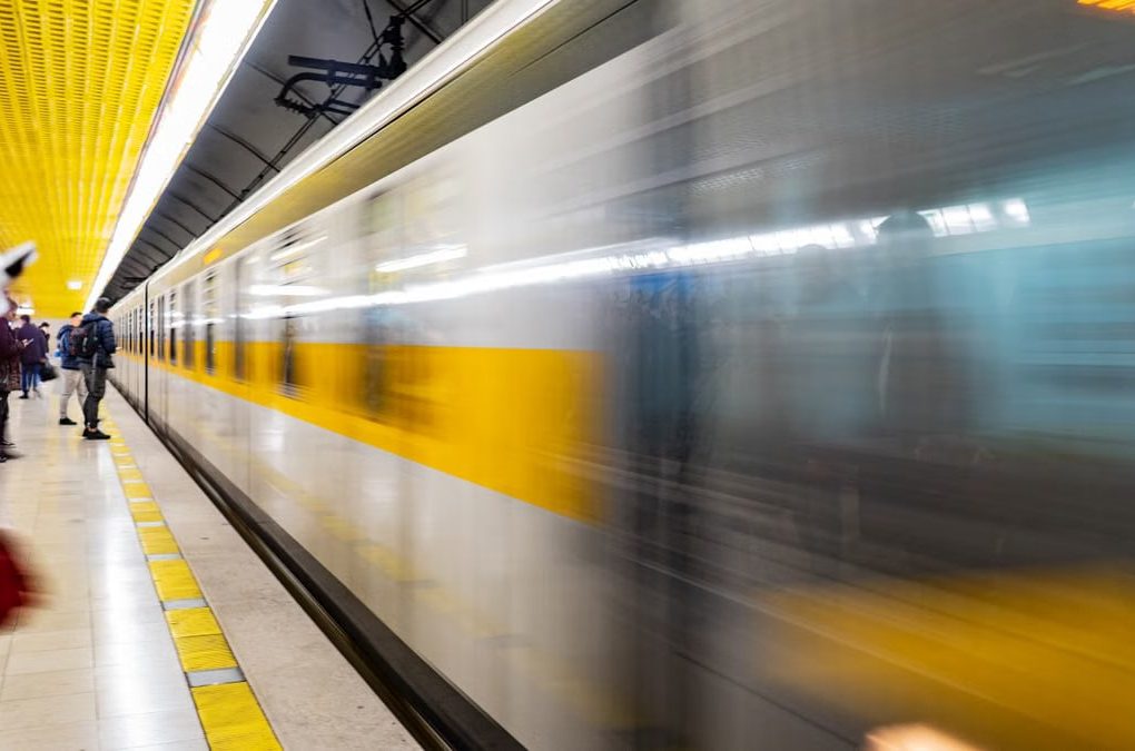 Blurred motion of a train speeding through a vibrant subway platform with commuters.