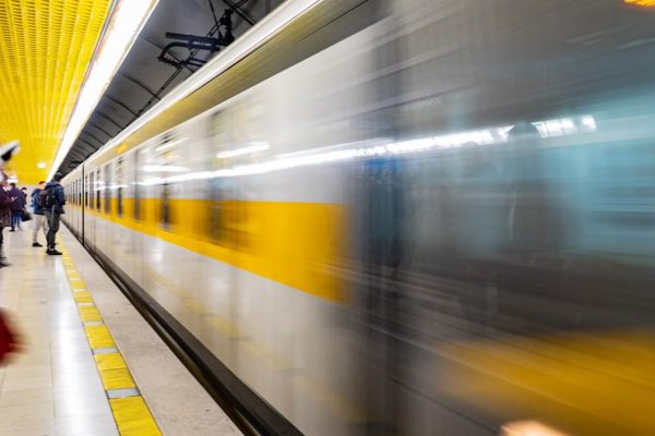Blurred motion of a train speeding through a vibrant subway platform with commuters.